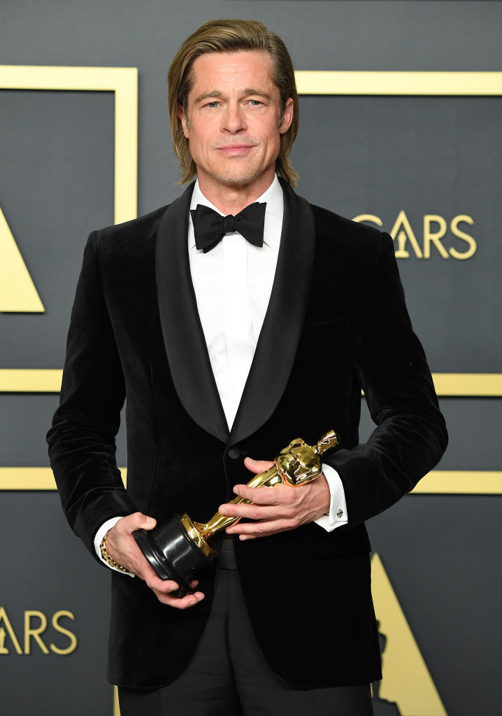 brad is holding his oscar on the red carpet