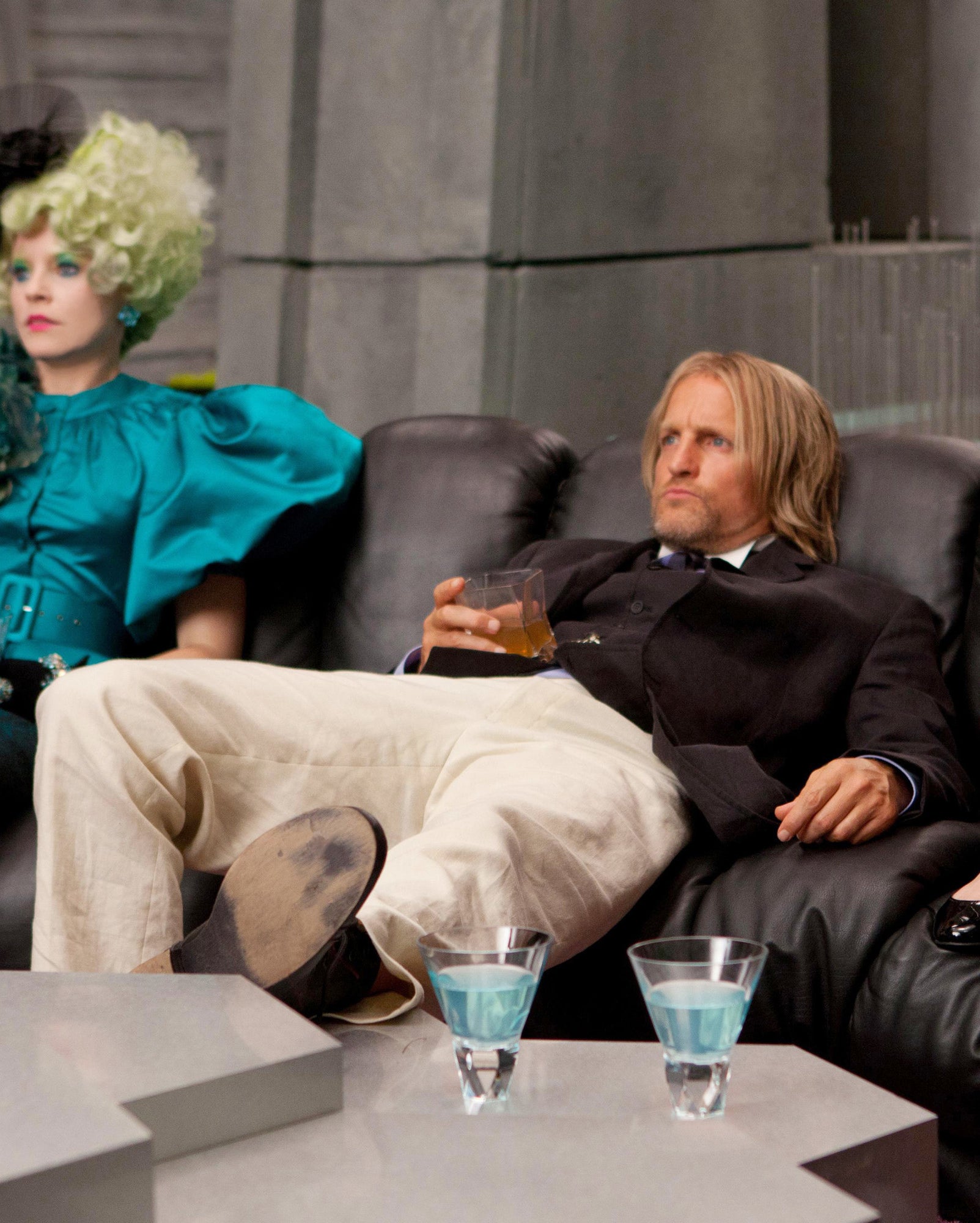 Haymitch in linen pants and a rumpled suit holding a drink