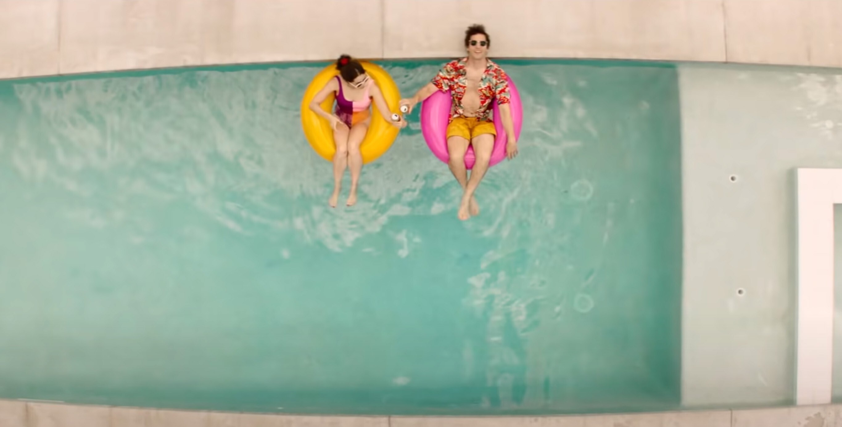Cristin Milioti和安迪·山姆伯格从上面漂浮在innertubes池在棕榈泉。