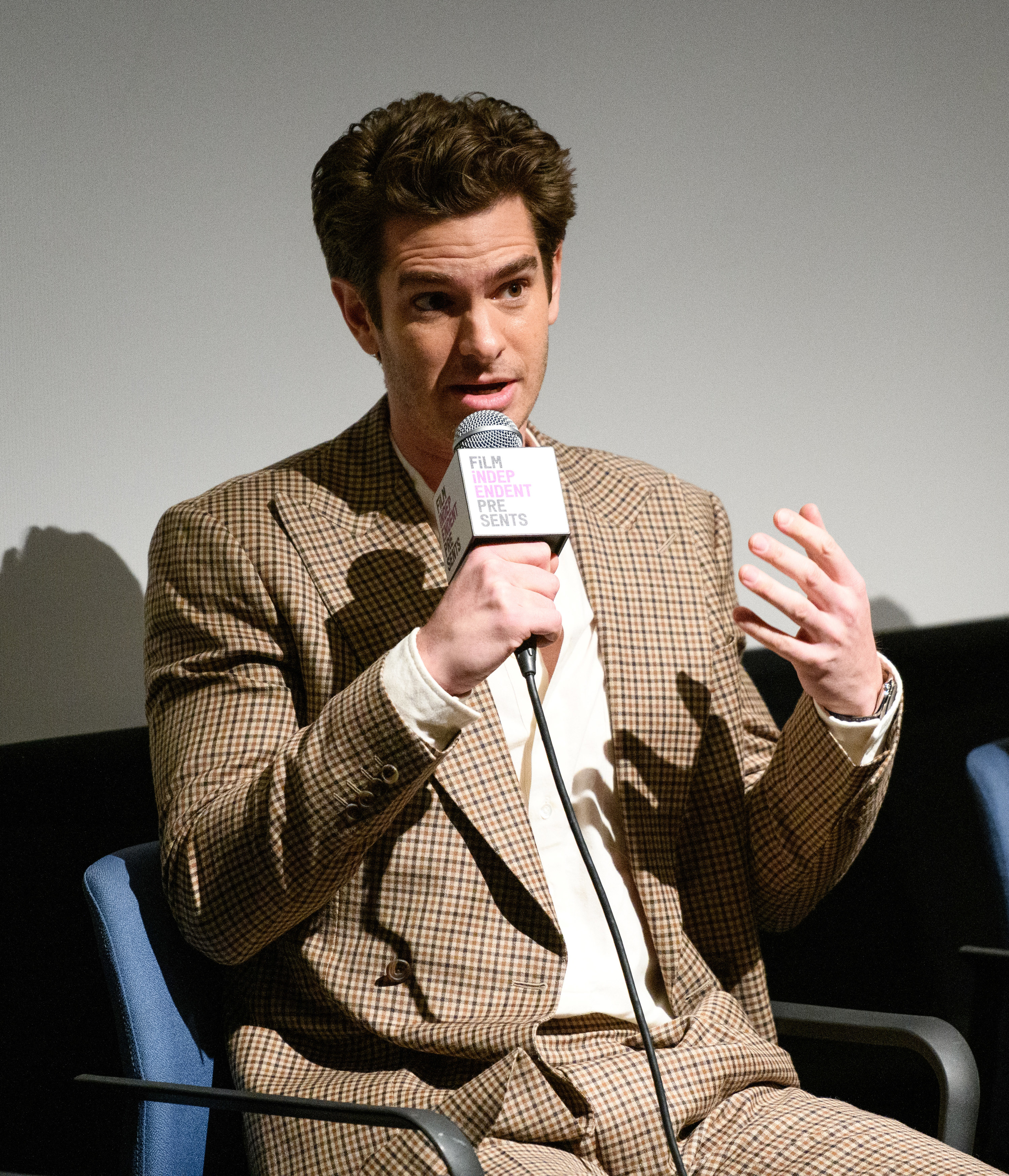 Andrew holding a microphone and speaking onstage