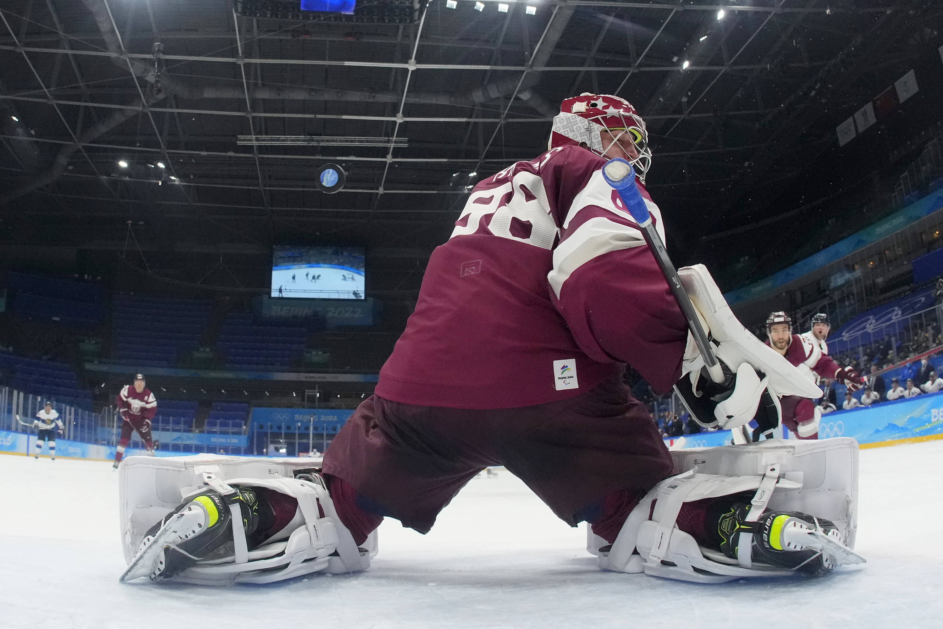 The goal keeper for the Latvian hockey trying to block a shot