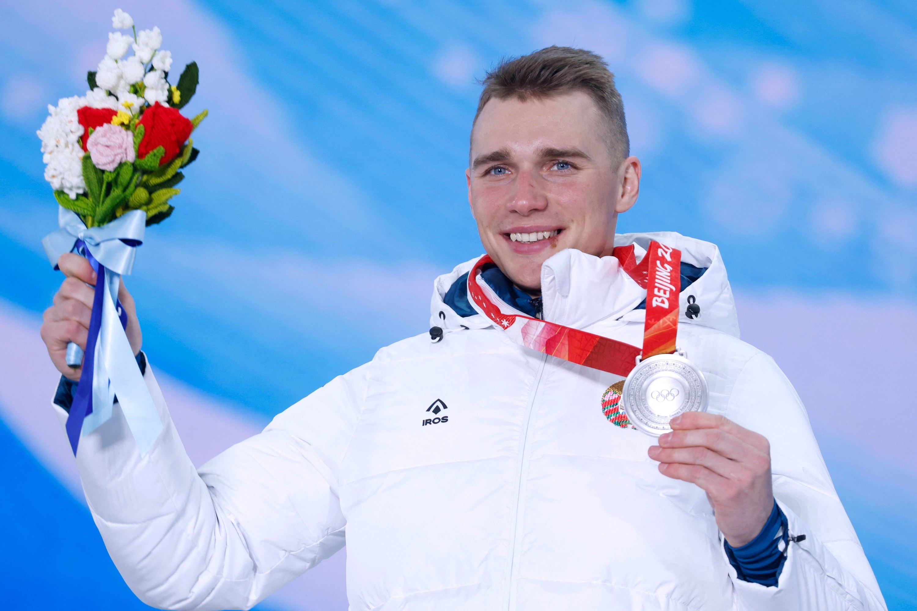A Bulgarian athlete holding up his silver medal and flower bouquet