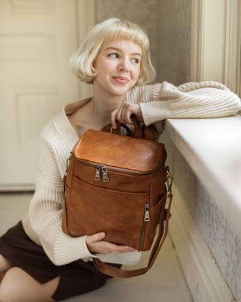 Model holding brown backpack