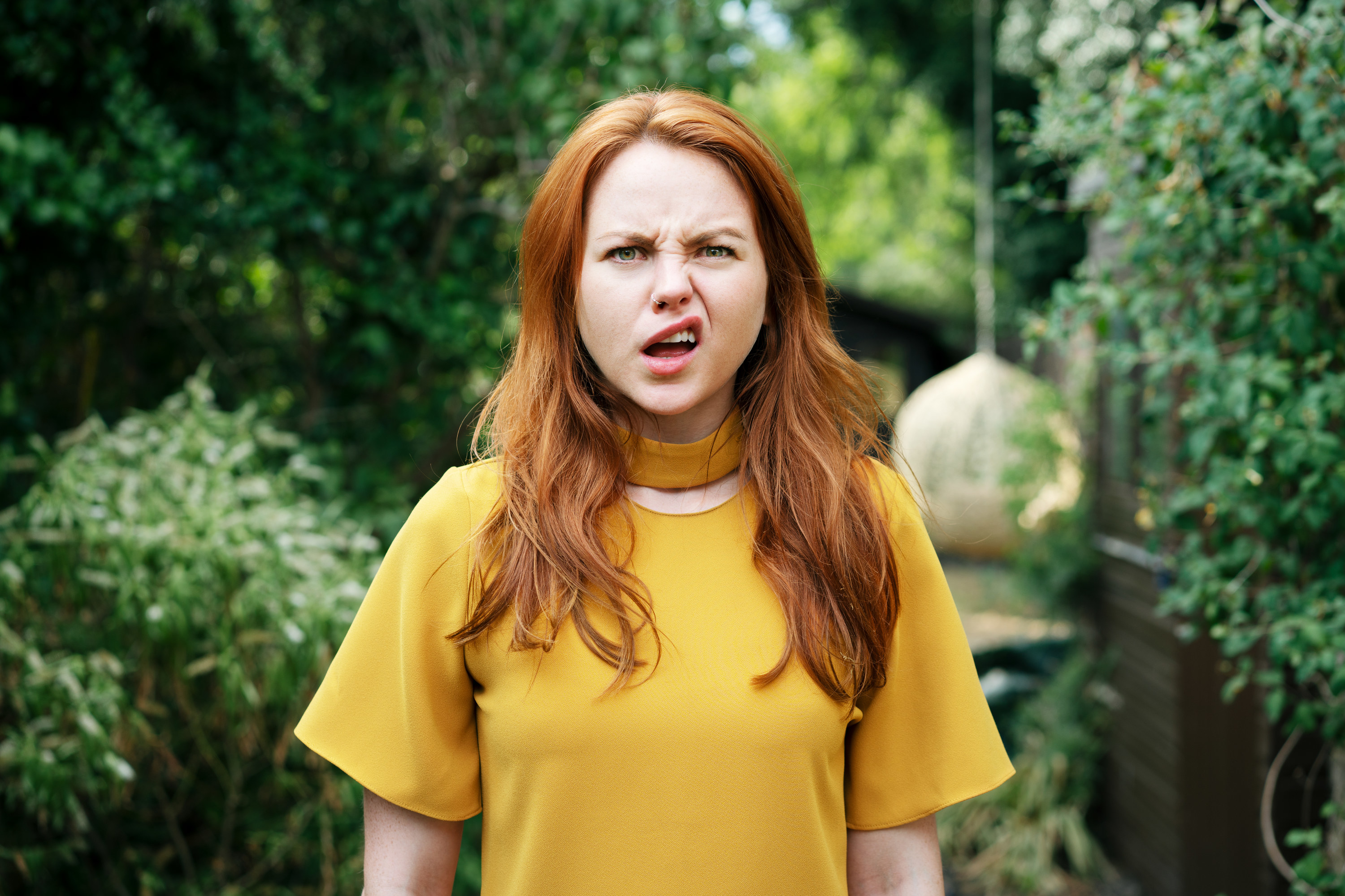 Woman in yellow shirt standing outside looking shocked