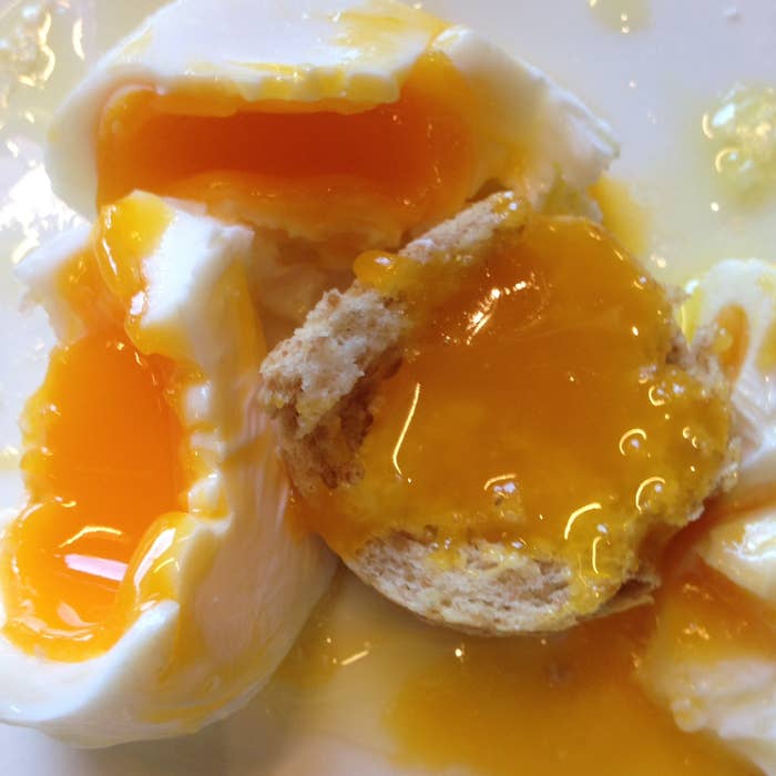 A soft poached egg spills its runny yolk onto the plate.