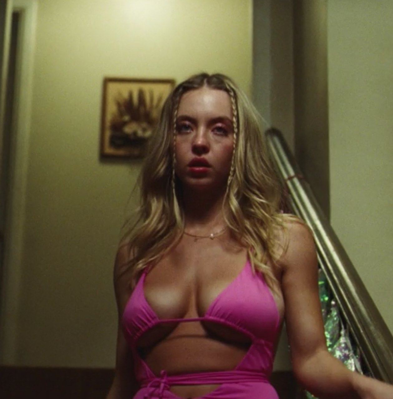 Cassie walks down the stairs while wearing a bright pink swimsuit