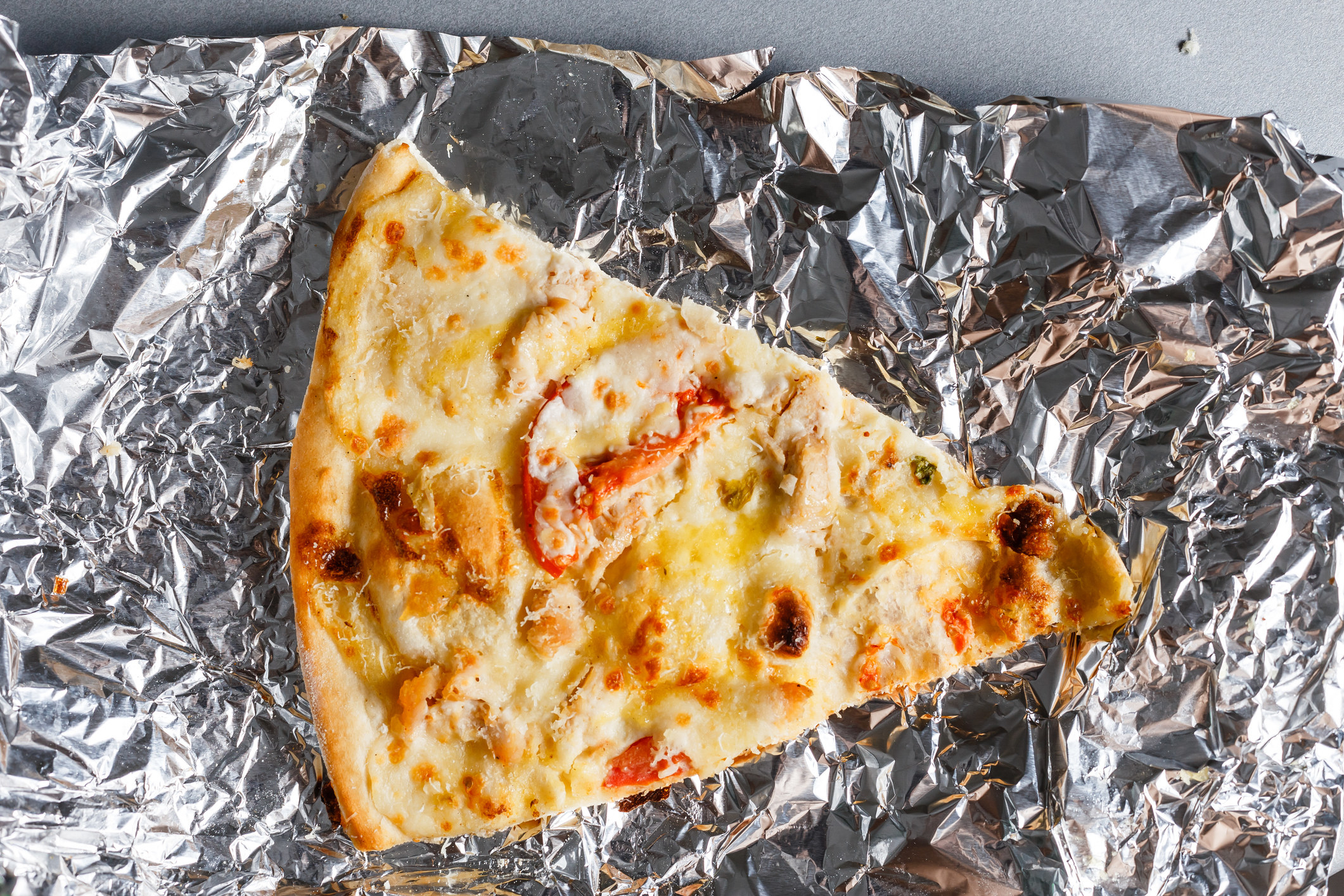 A slice of cold pizza on foil.