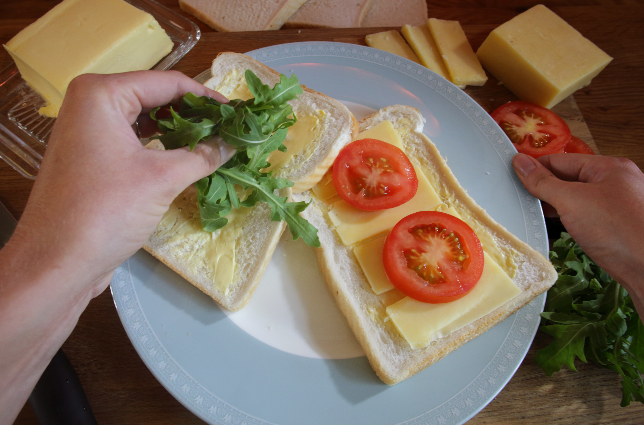 Making a cheese, tomato, and arugula sandwich.