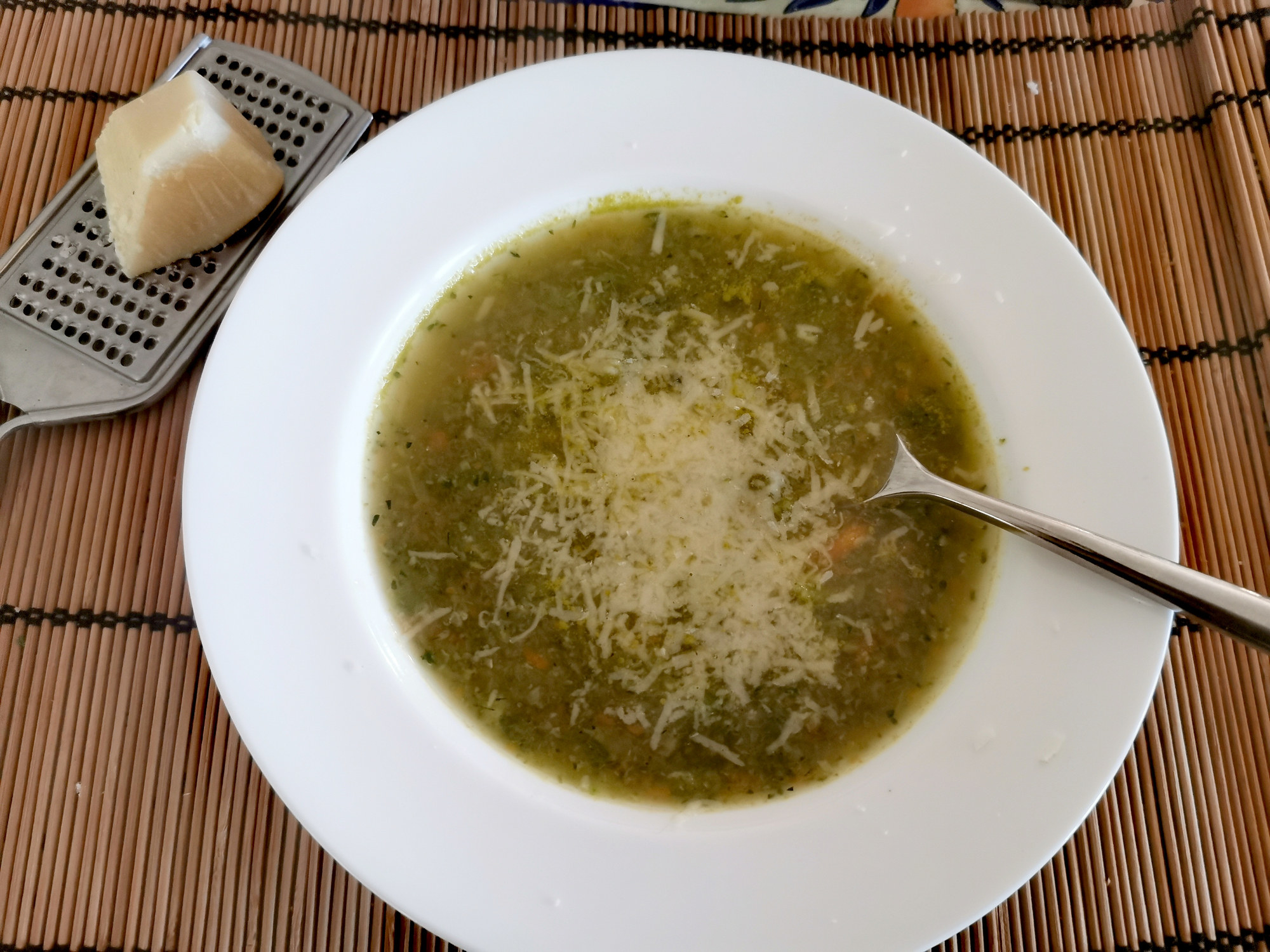 A bowl of soup topped with shaved Parmesan.