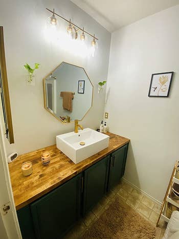 reviewer photo of the gold mirror hanging above a bathroom sink
