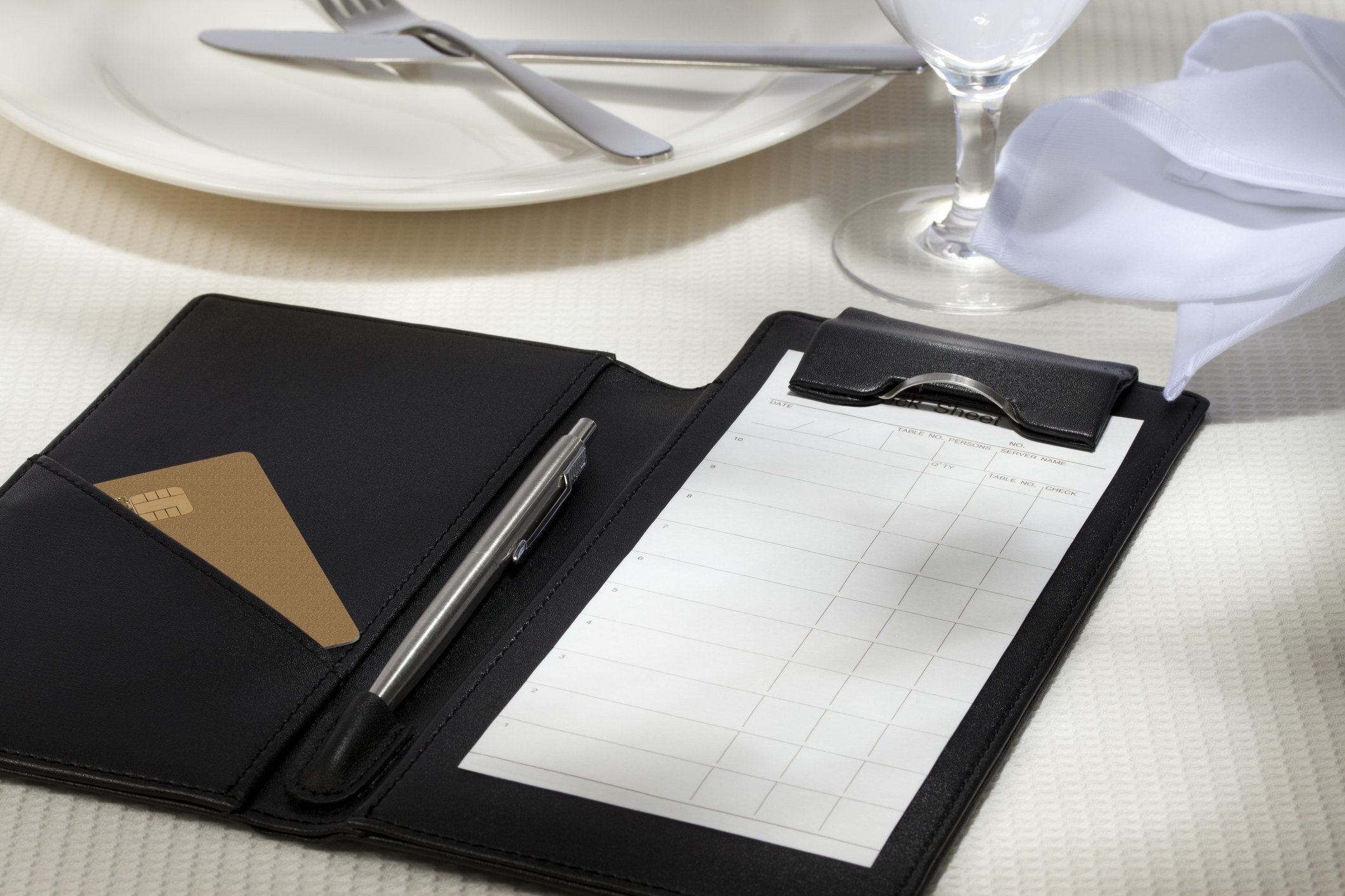 A stock image of a blank bill on a table at a restaurant