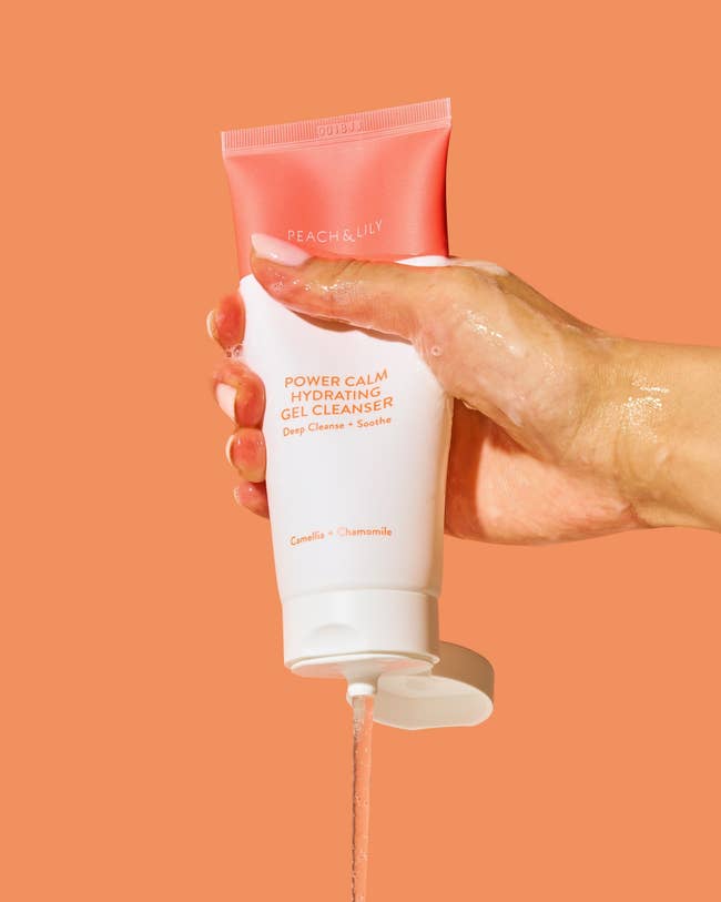 the bottle of cleanser being squeezed by a model's hand