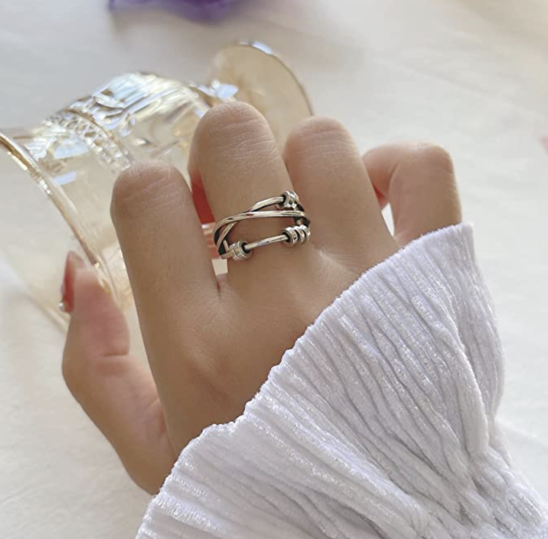 Someone&#x27;s hand with the fidget ring on their middle finger
