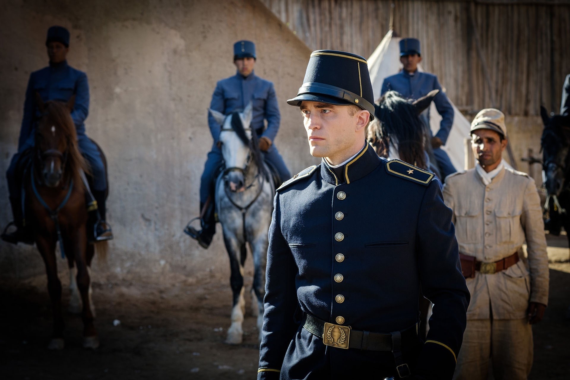Robert Pattinson looking stern in a 19th century navy-blue uniform