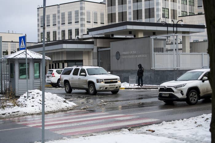 One person stands outside a gray building as a van goes by