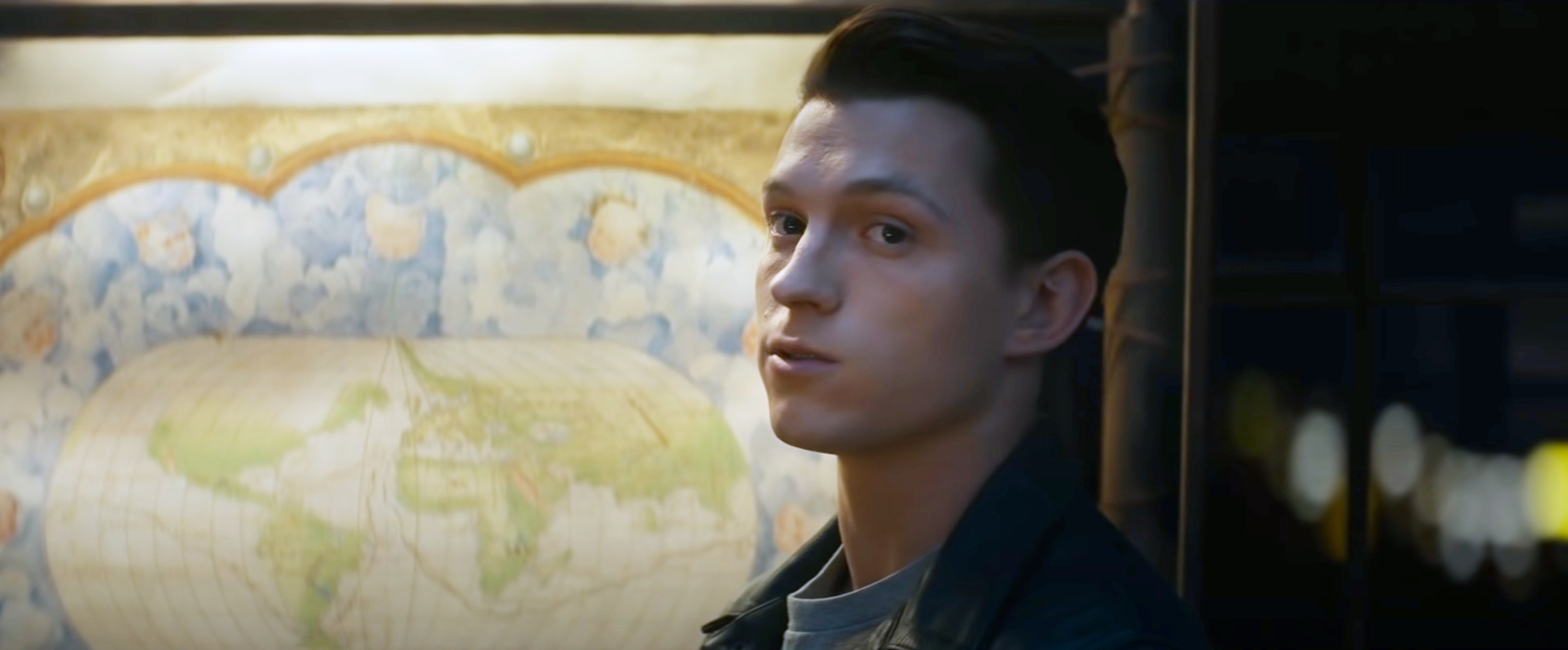 A closeup of Tom standing in front of a map in Uncharted
