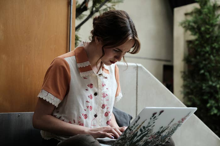 Teenage girl typing on flower-decal-covered MacBook