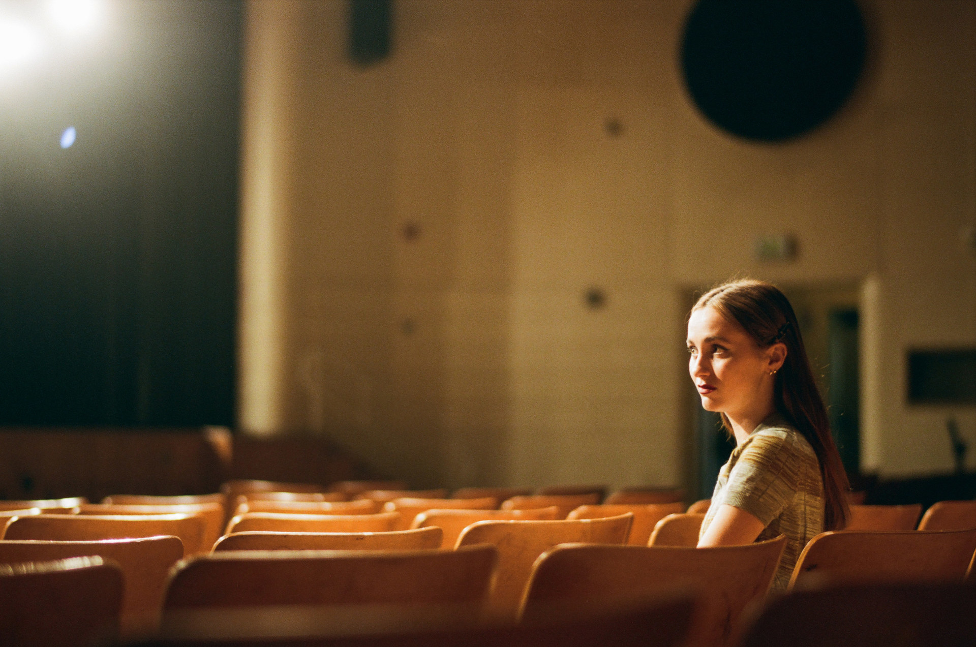 Teenage girl sitting in an empty high school auditorium