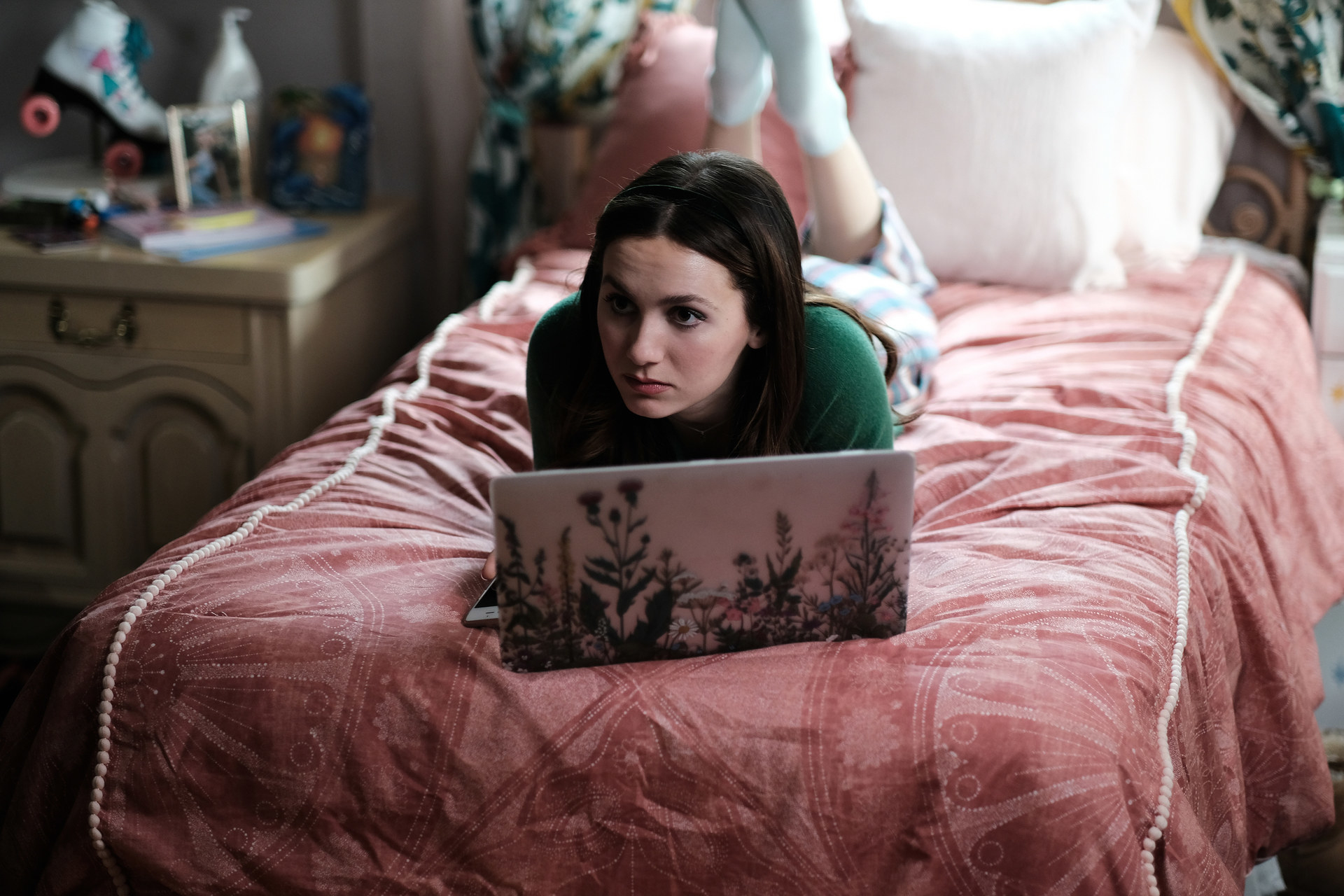 Teenage girl lying down on bed with her Macbook