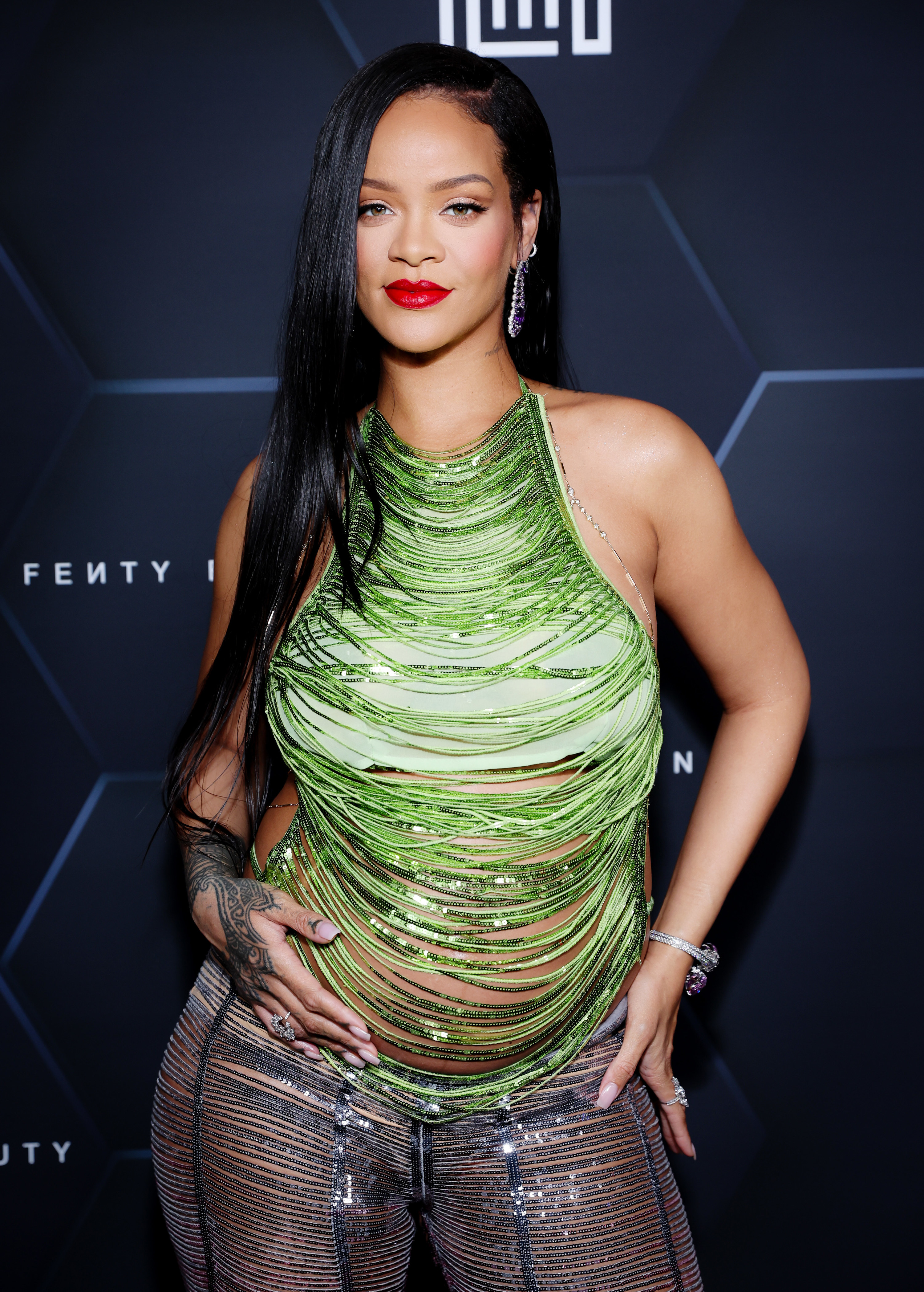 Rihanna holds her baby bump at a step-and-repeat