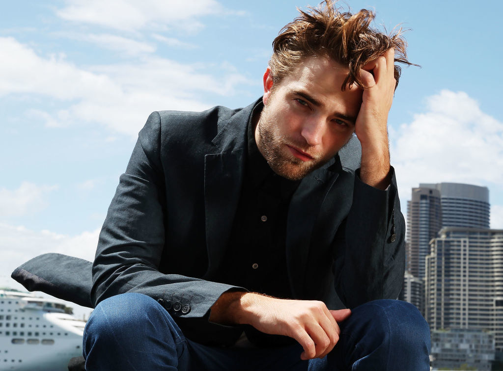 Robert Pattinson poses with his head on his hand during a photo call