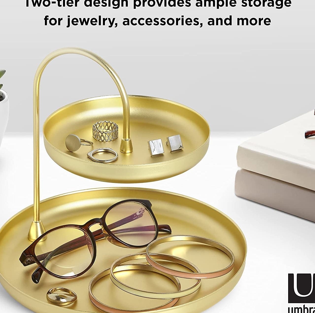 The trinket tray sitting on a table with bracelets, rings, cufflinks, and glasses sitting inside of it