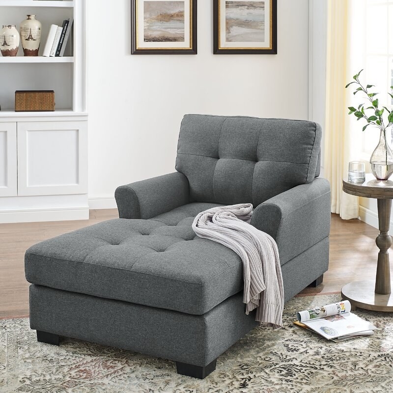 Gray chaise lounge with a throw next to a round end table