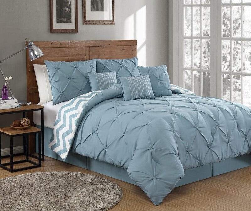 Blue comforter set shown on a wood bed