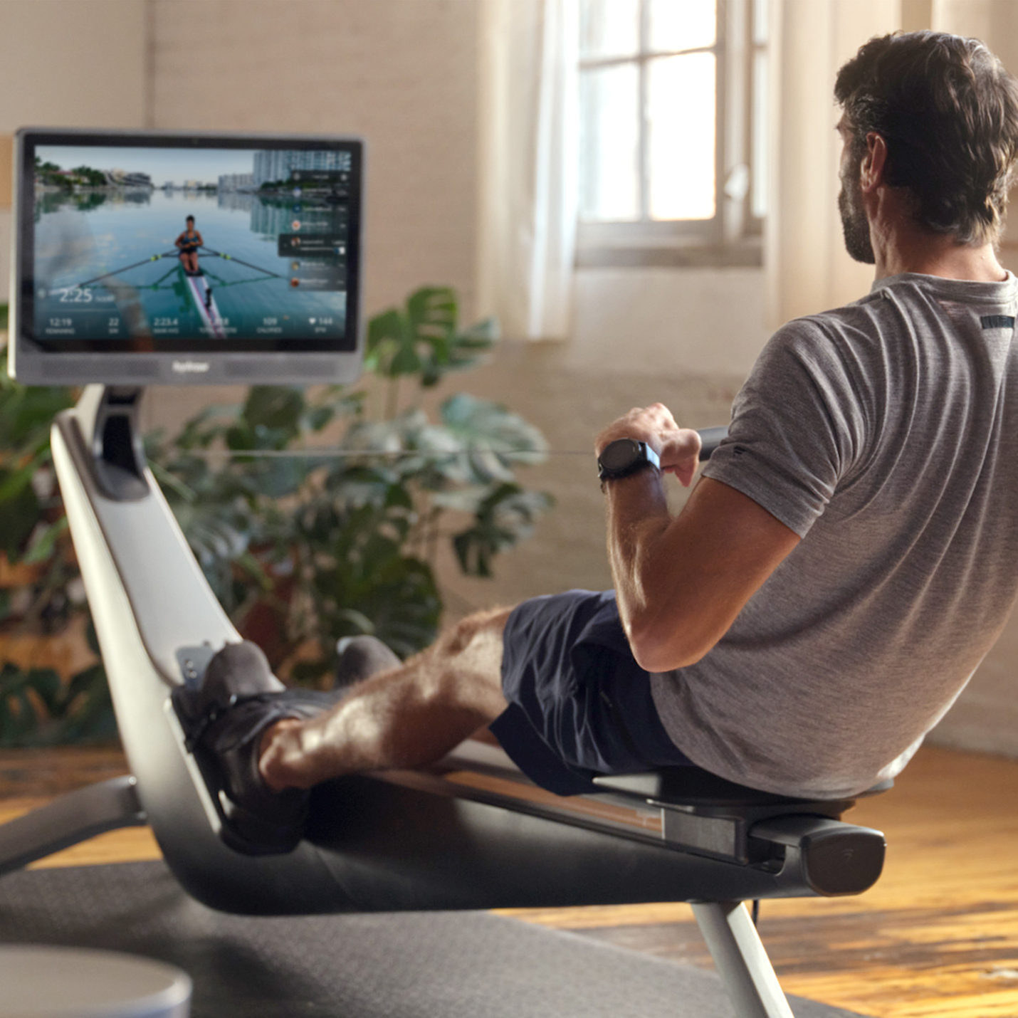 person using the rowing machine following along to a rowing video on the screen