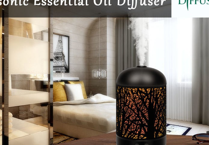 The diffuser with a tree design etched into the sides sitting on a table in a bedroom