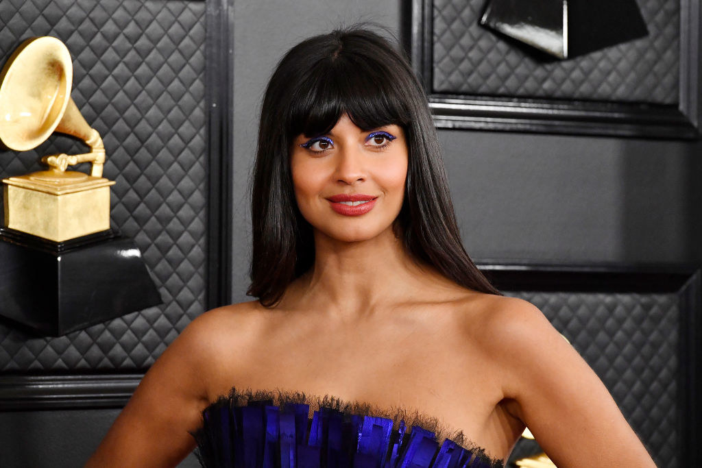 at the Grammys, Jamila poses on the red carpet with her hands on her hips, and her bold eyeshadow matches her sleeveless, pleated gown