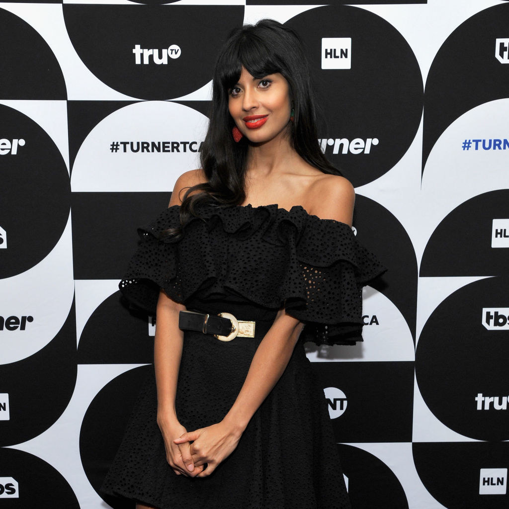 on a press tour, Jameela holds her hands in front of her in a sleeveless, ruffly dress