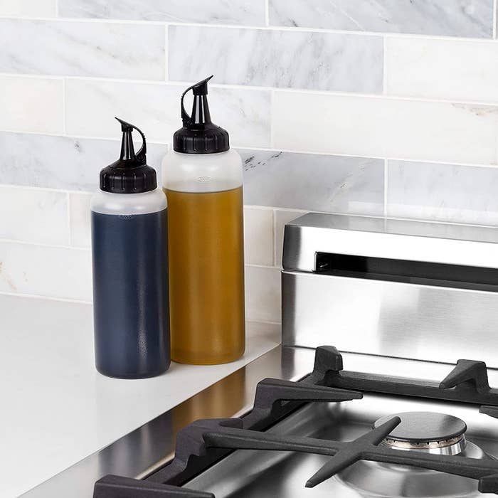 Two squeeze bottles on a counter next to a stove