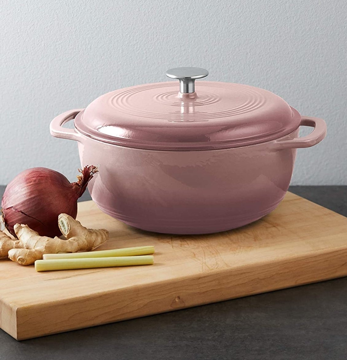 A dutch oven on a cutting board next to ingredients