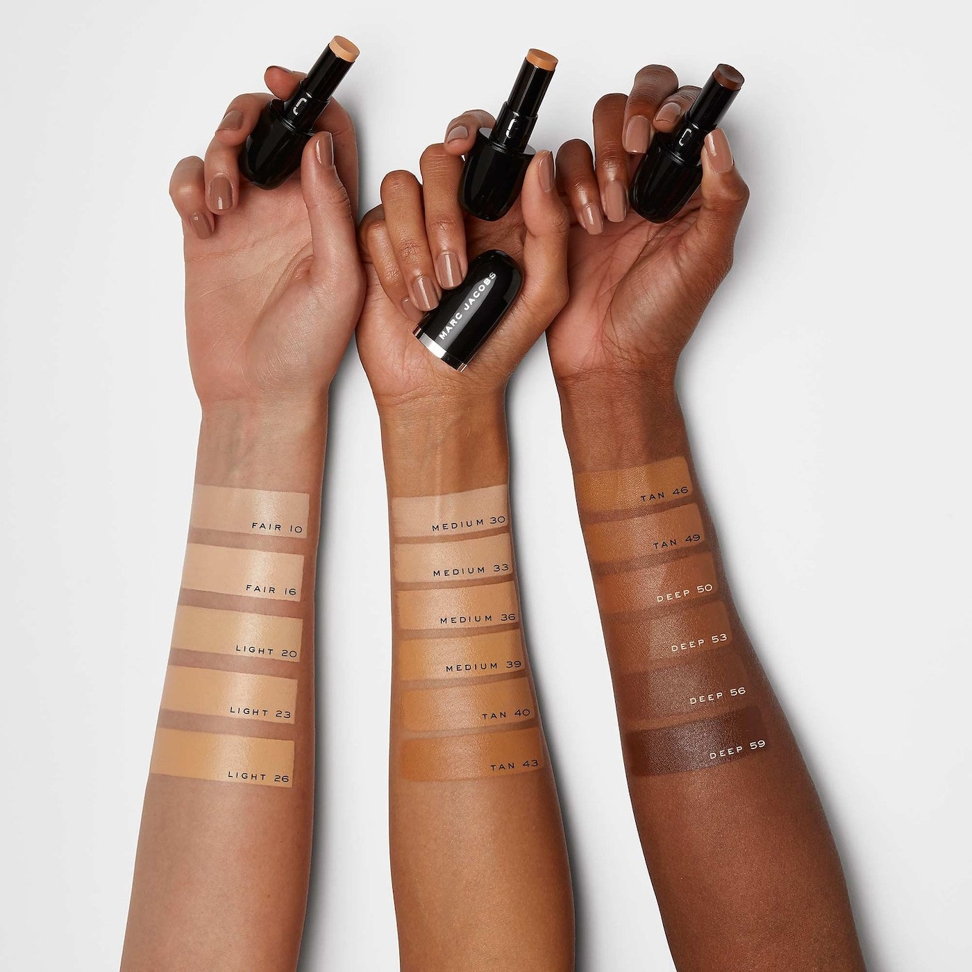 models with different skin tones wear various shades of the Marc Jacobs Beauty concealer stick on wrists