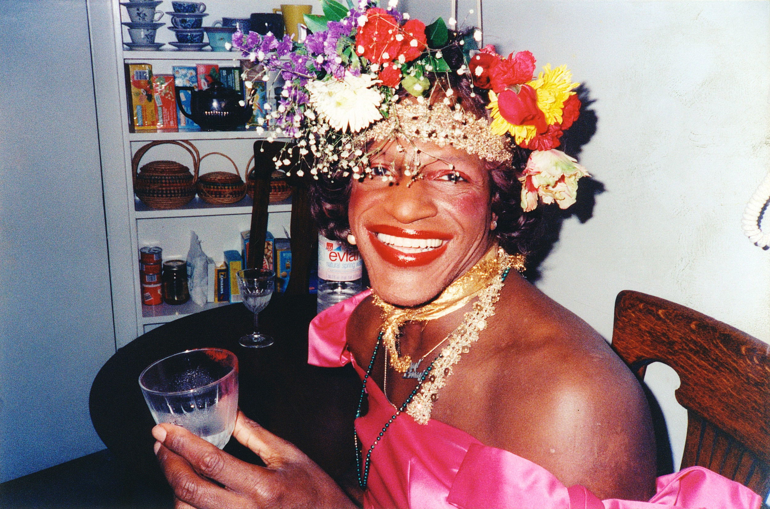 A Black woman with flowers in her hair holding a cup