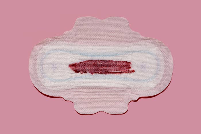 Stock image of a menstrual pad with blood on it, pink background