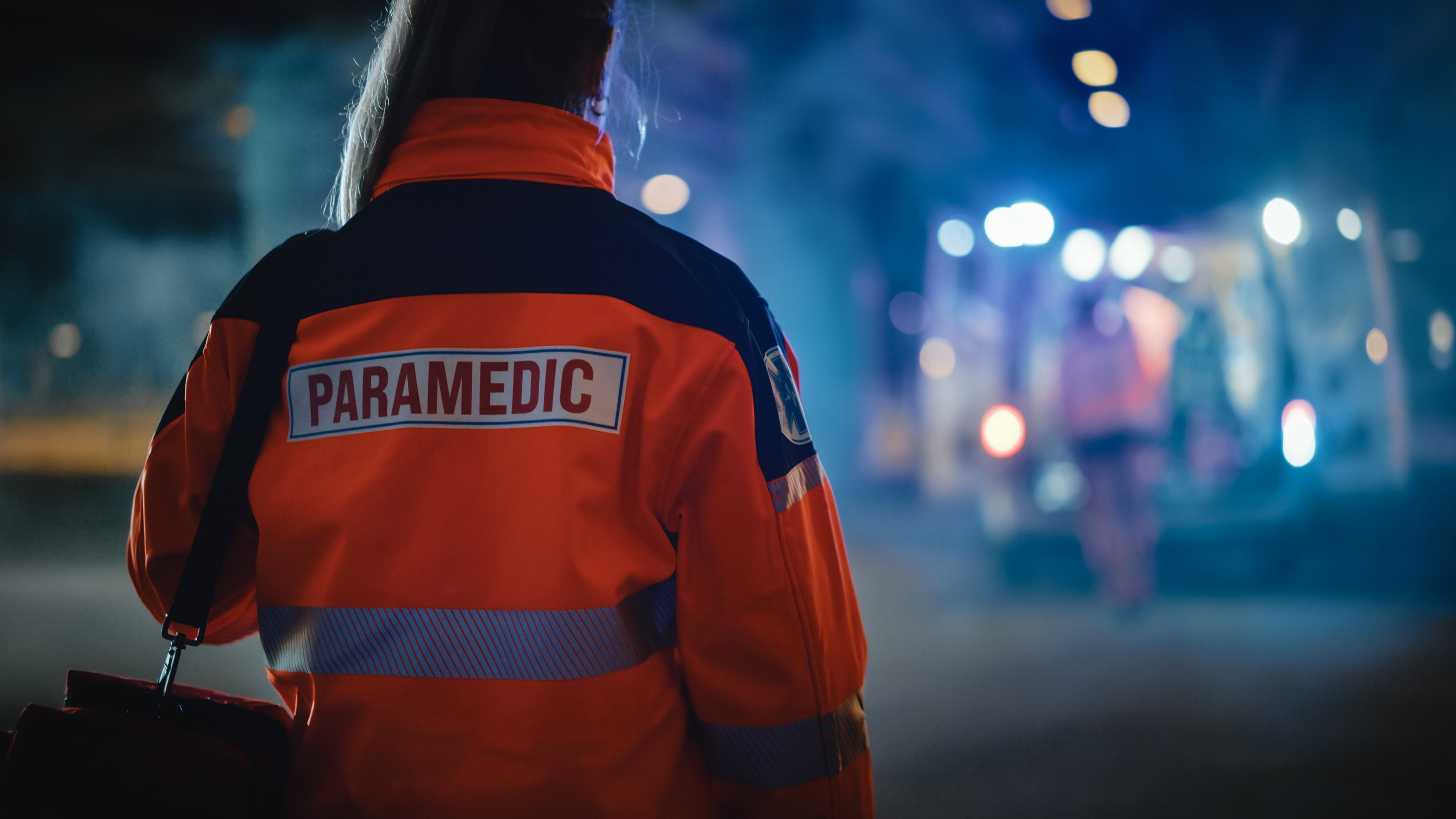 the back of a paramedic who&#x27;s facing an ambulance