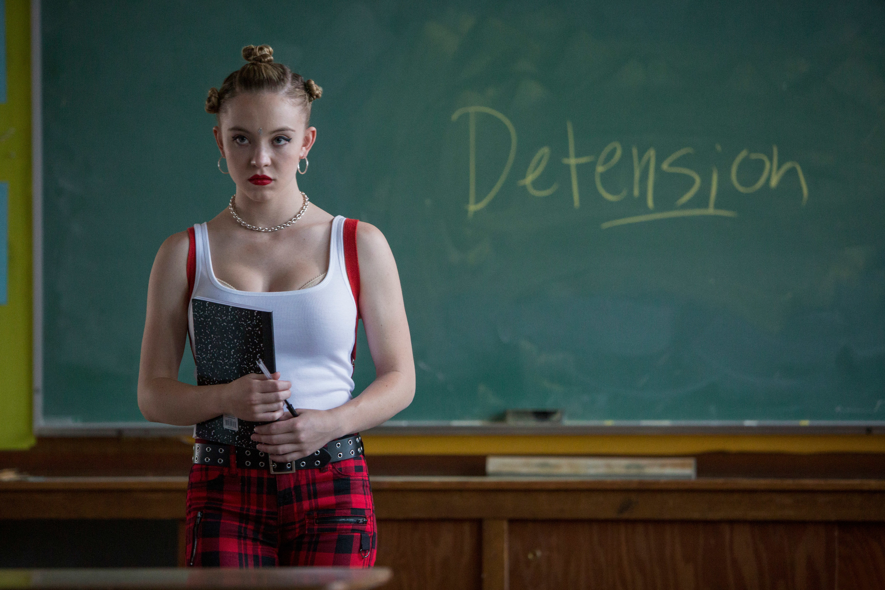 Sydney holding a notebook while standing in front of a chalkboard that says Detension