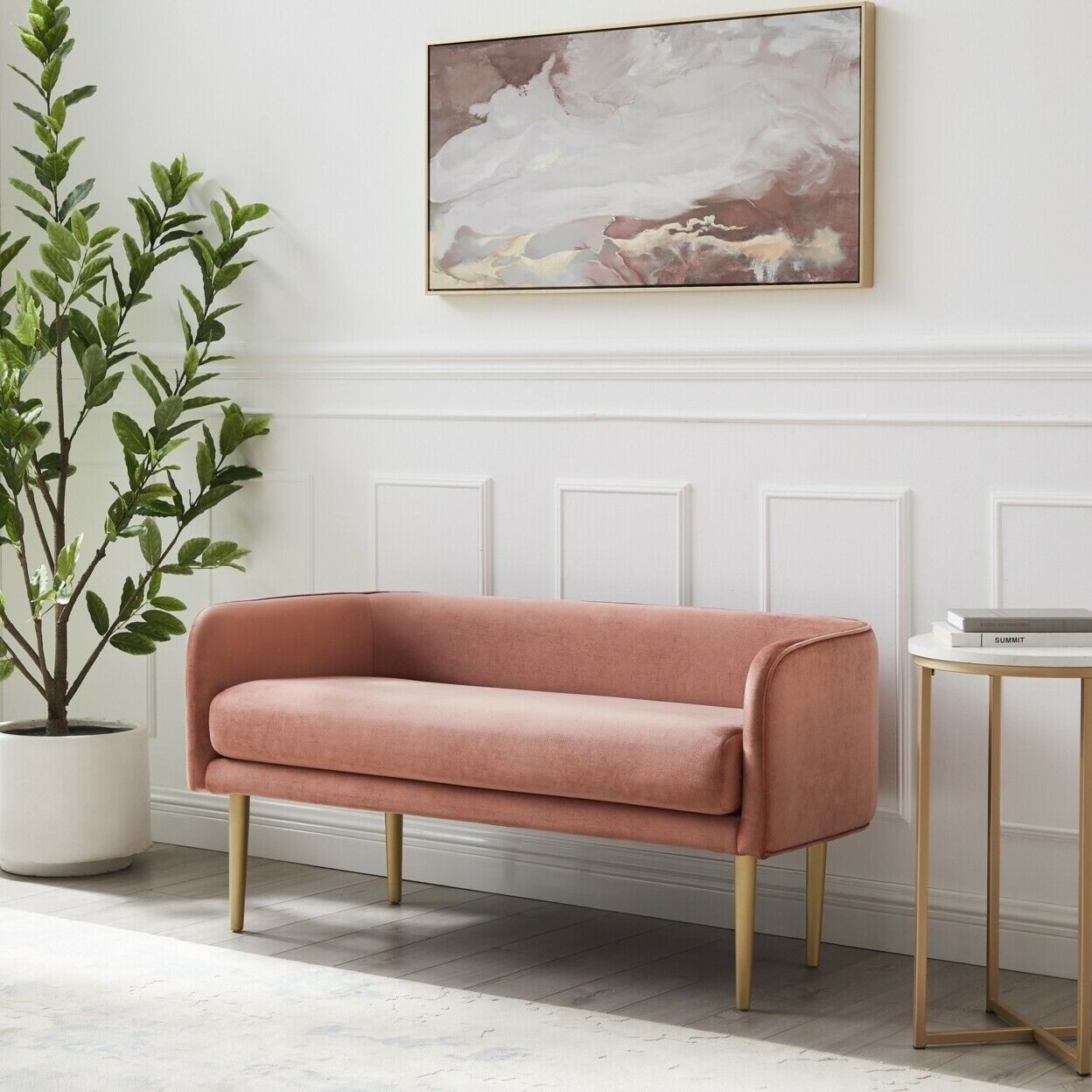 a salmon pink rounded bench with gold legs