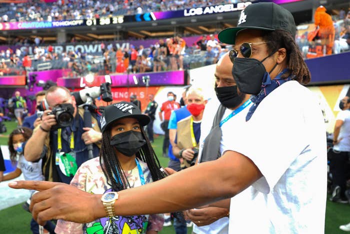 Jay and Blue wearing face masks and fitted caps as they stand on the sideline