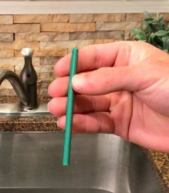 Someone holding up a drain stick over a sink