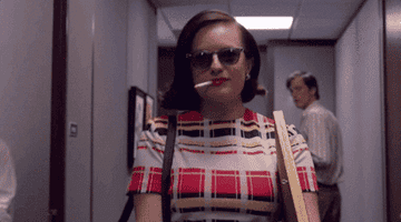 Peggy from &quot;Mad Men&quot; walking down the hall of her job with a cigarette in her mouth
