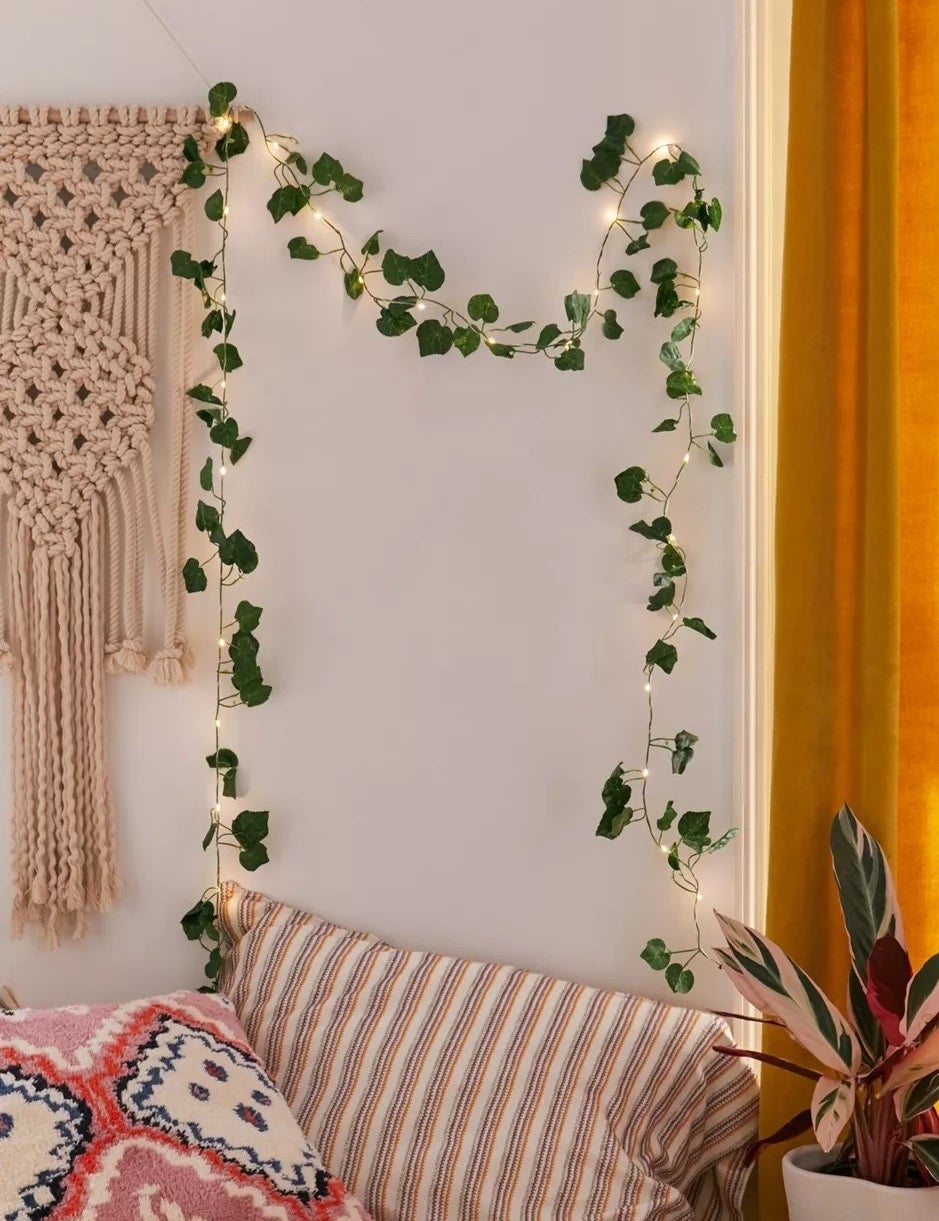 The vines hanging on a wall above a body pillow and various other decor