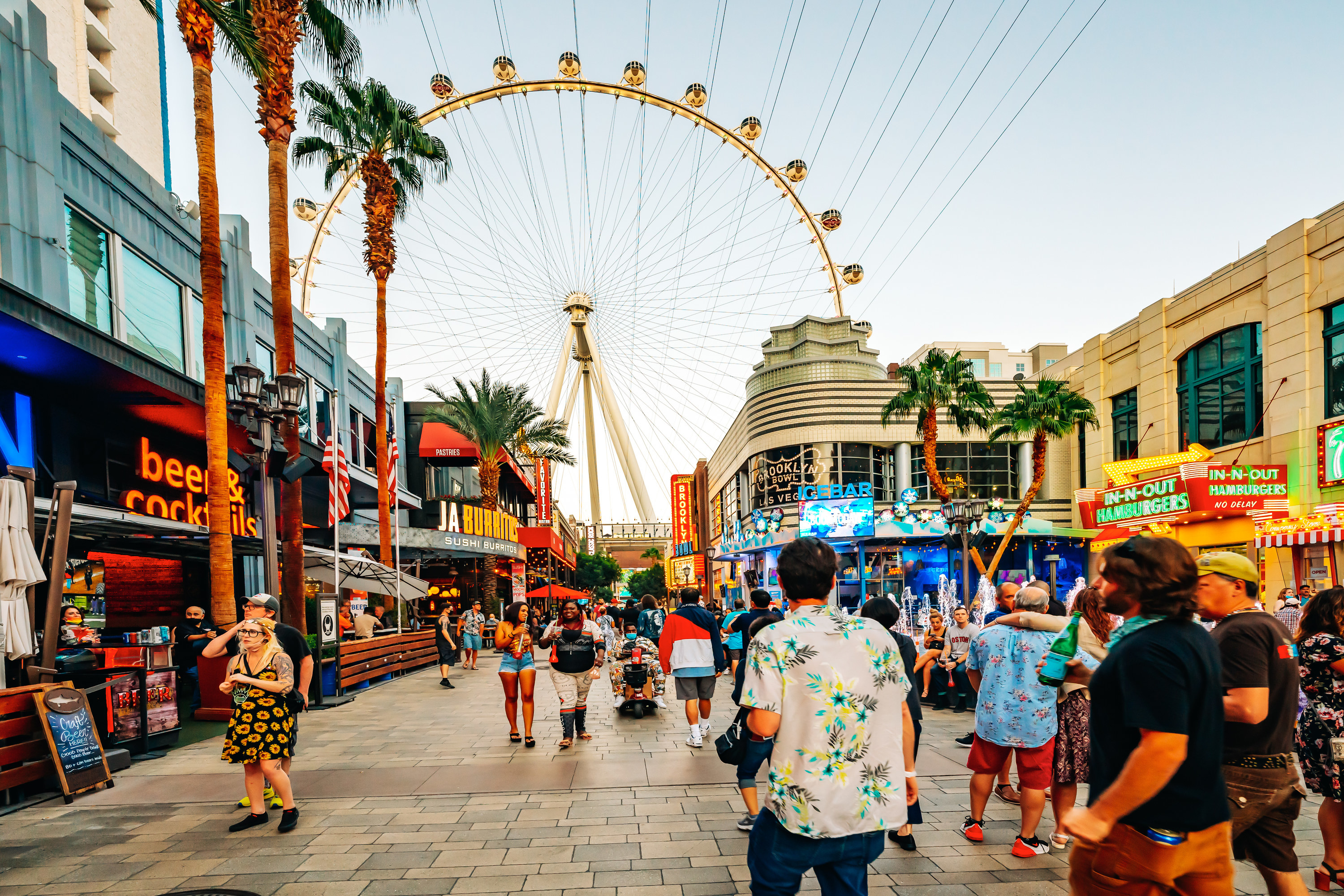 People walk in front of the ferris wheel at the Las Vegas strip on a sunny day