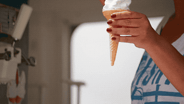 A woman hands a man an ice cream cone