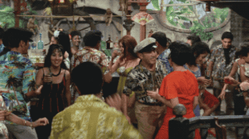 An old movie clip featuring people dancing at a tropical party