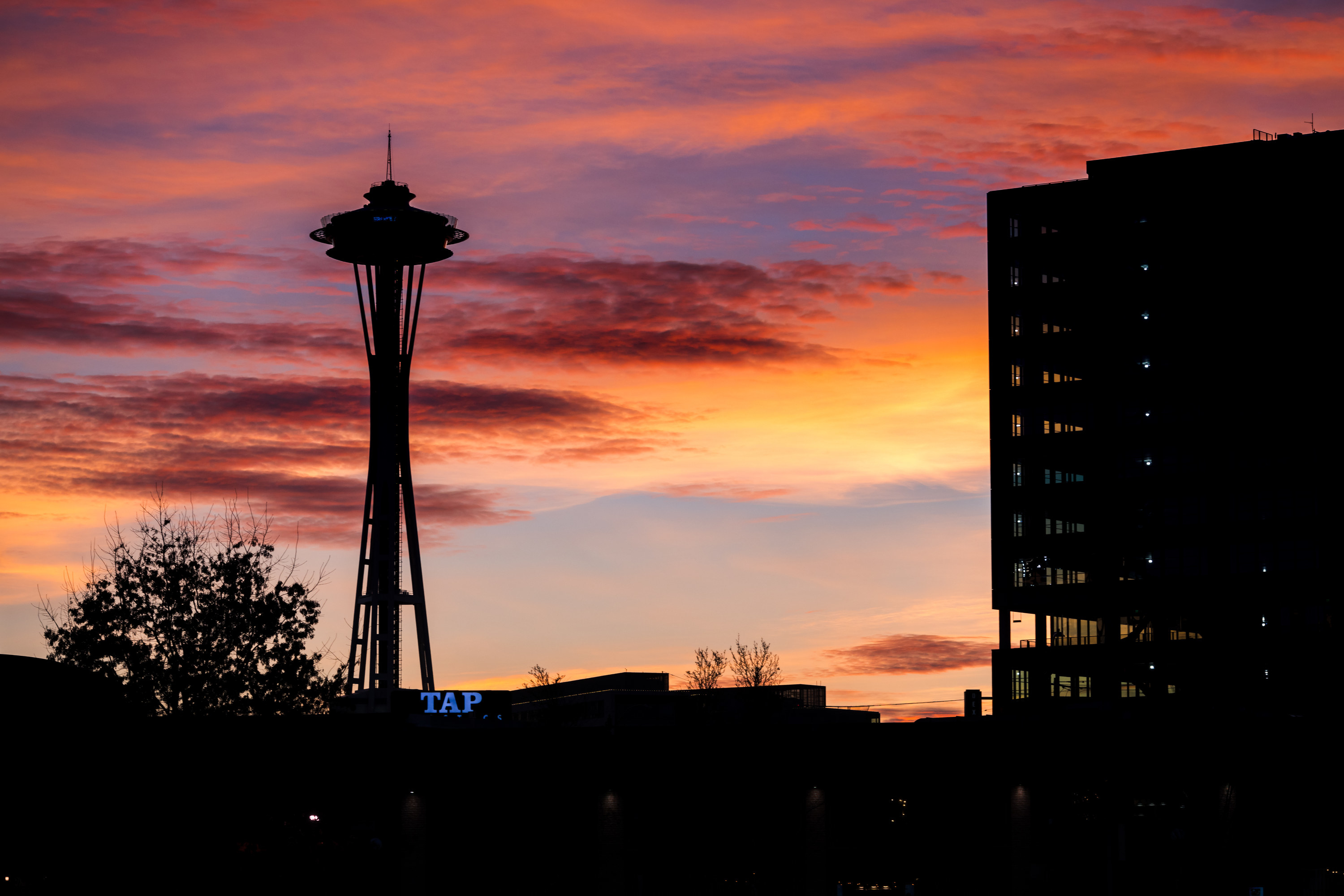 The Space Needle in Seattle, WA in front of a bright orange and pink sunset