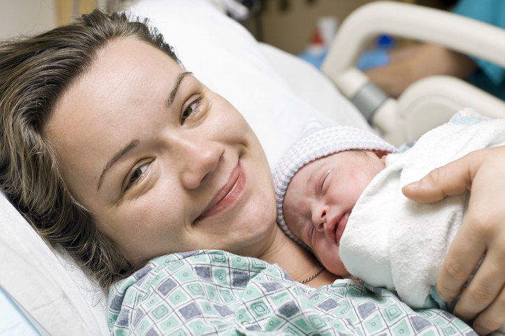 Woman looking fresh and smiling while holding her newborn baby