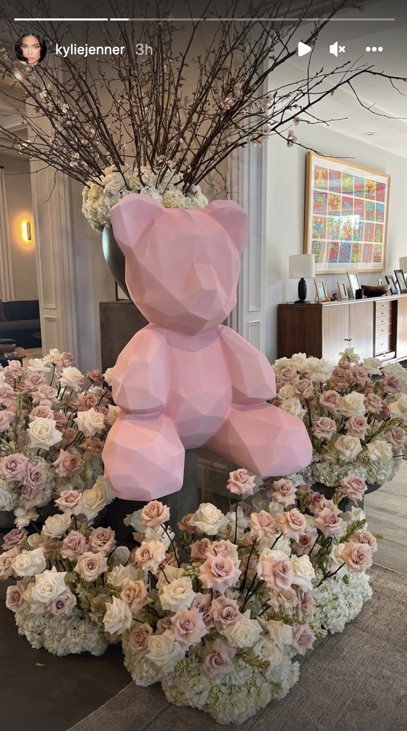 A sculpture of a pink bear surrounded by roses
